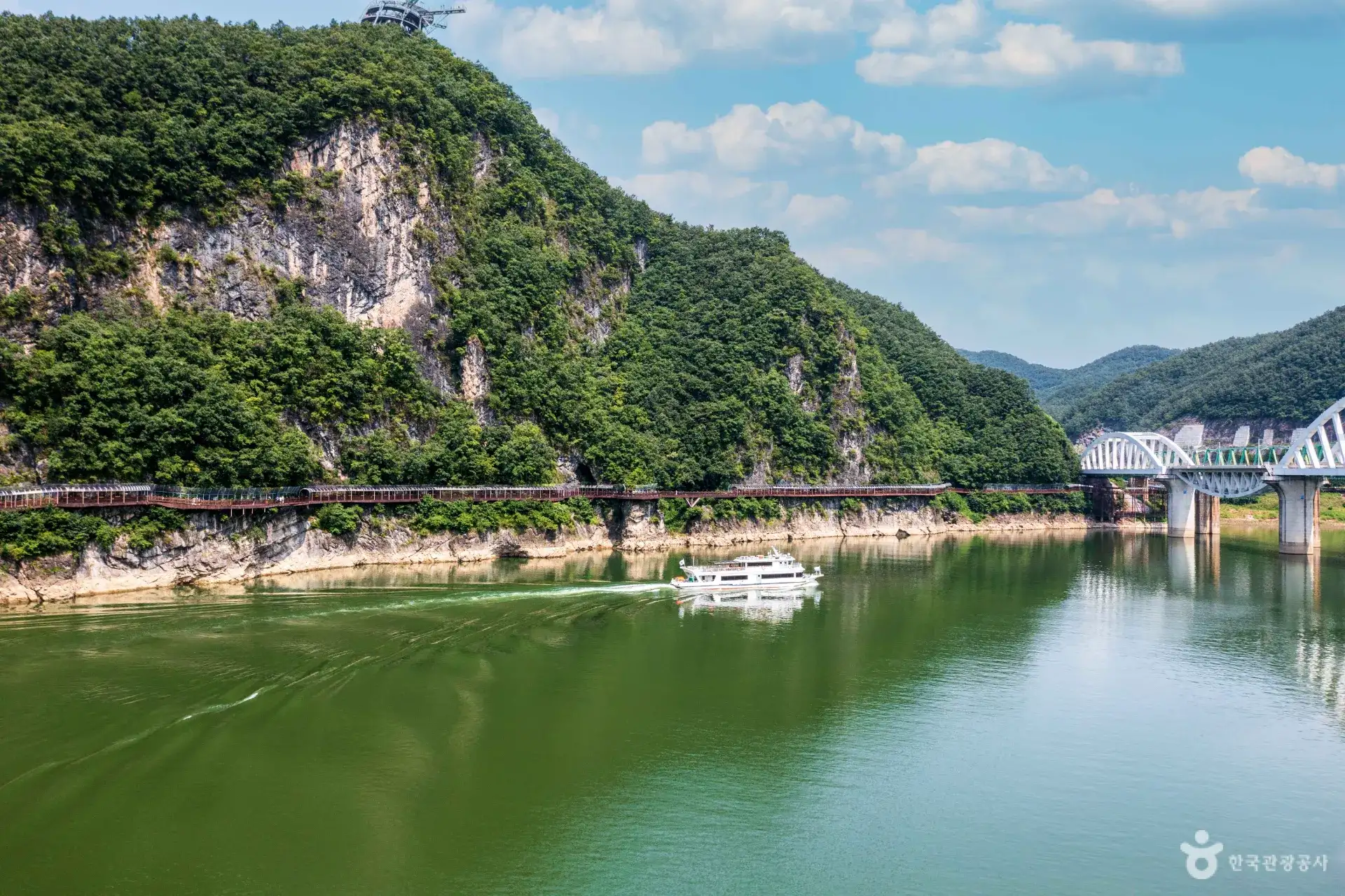 A covered wooden walkway built along a steep river cliff