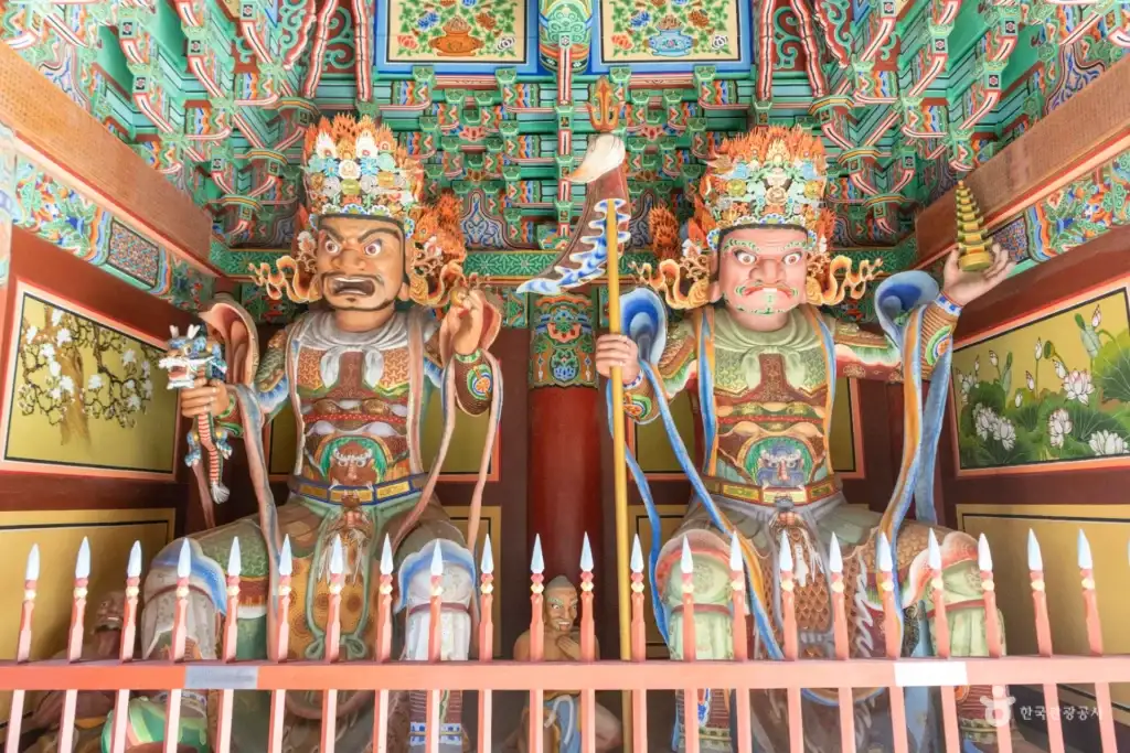 Two colorful Four Heavenly Kings statues inside a temple