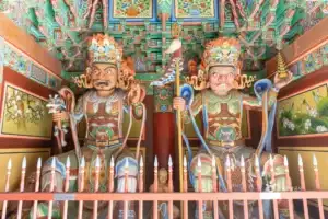 Two colorful Four Heavenly Kings statues inside a temple