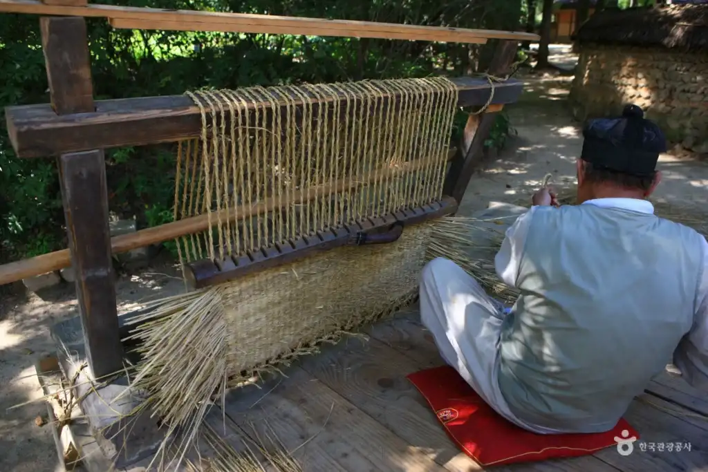 Artisan weaving straw shoes at folk village